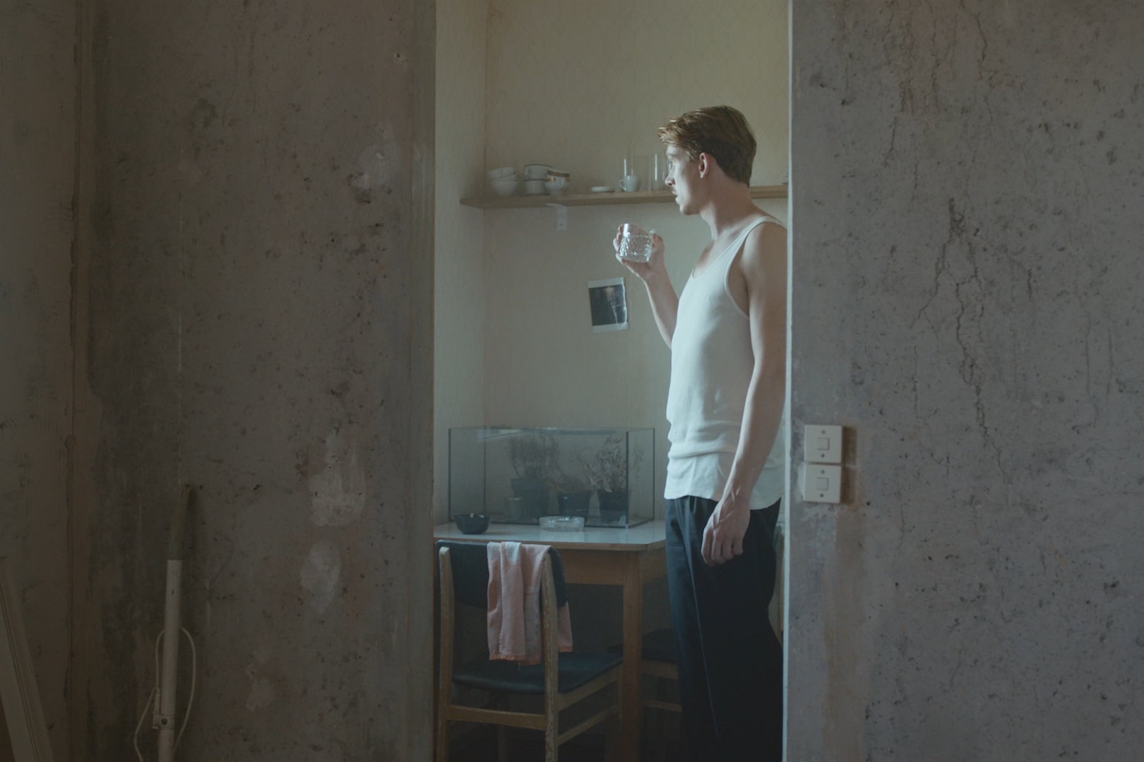 Man standing in the kitchen, holding a glass of water.