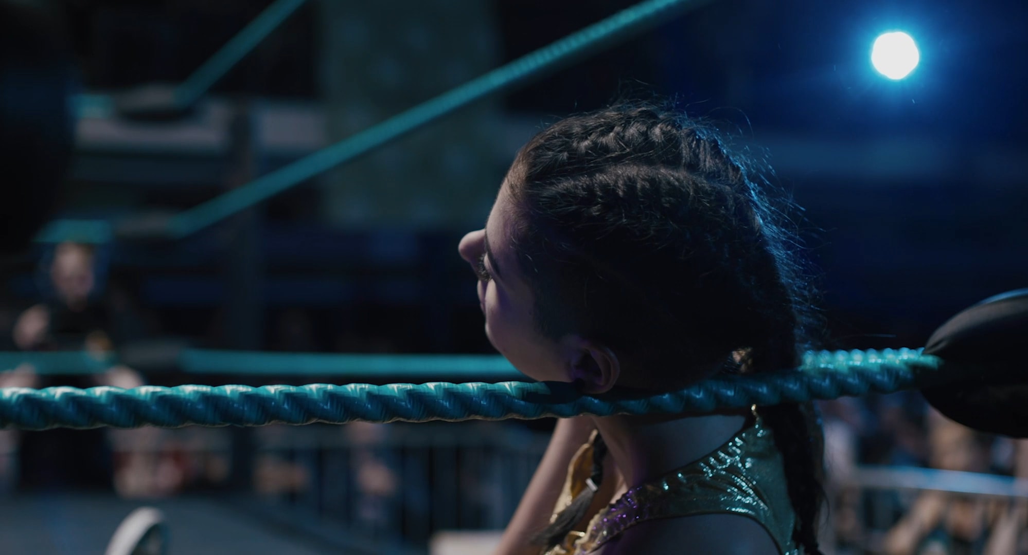 A young woman, exhausted, leaning against the side of the wrestling ring.