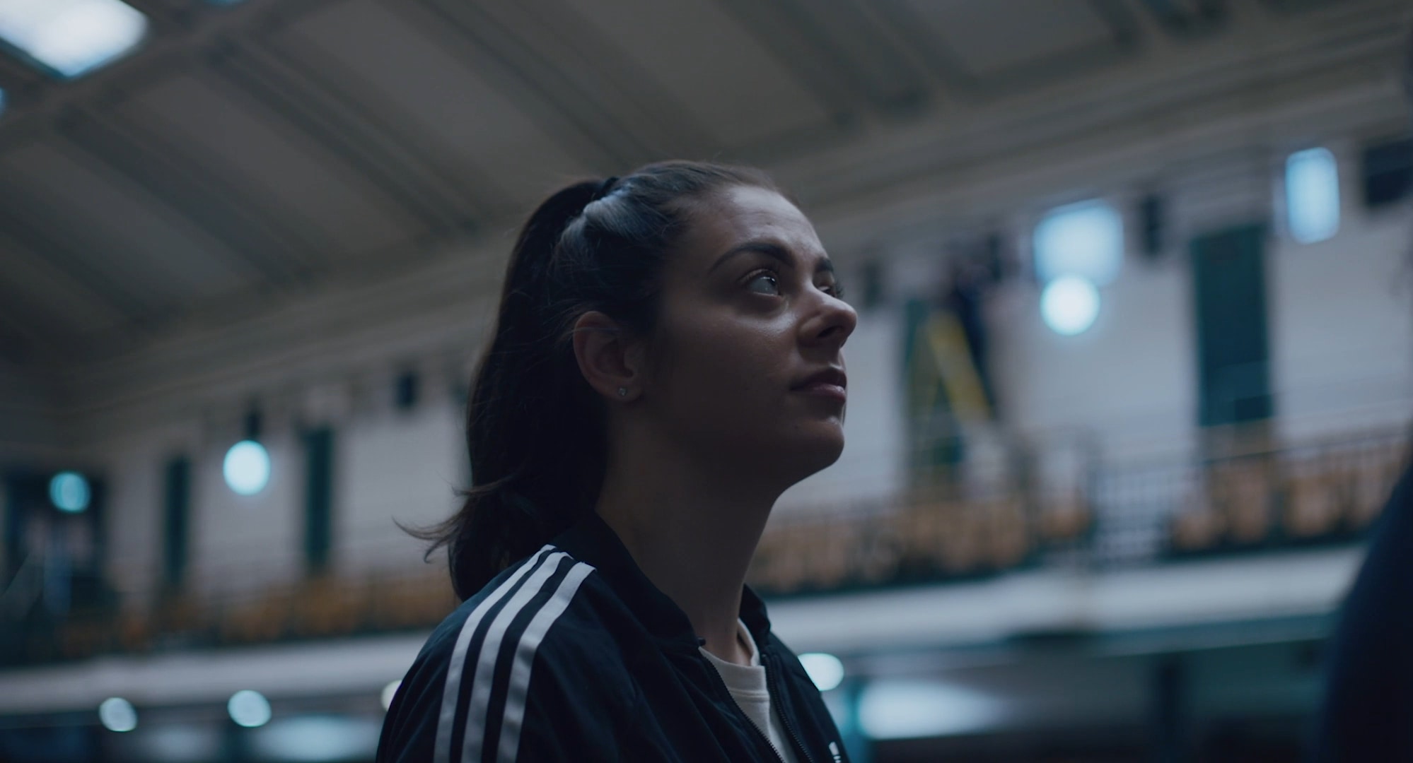 A young woman in a large hall, looking up.