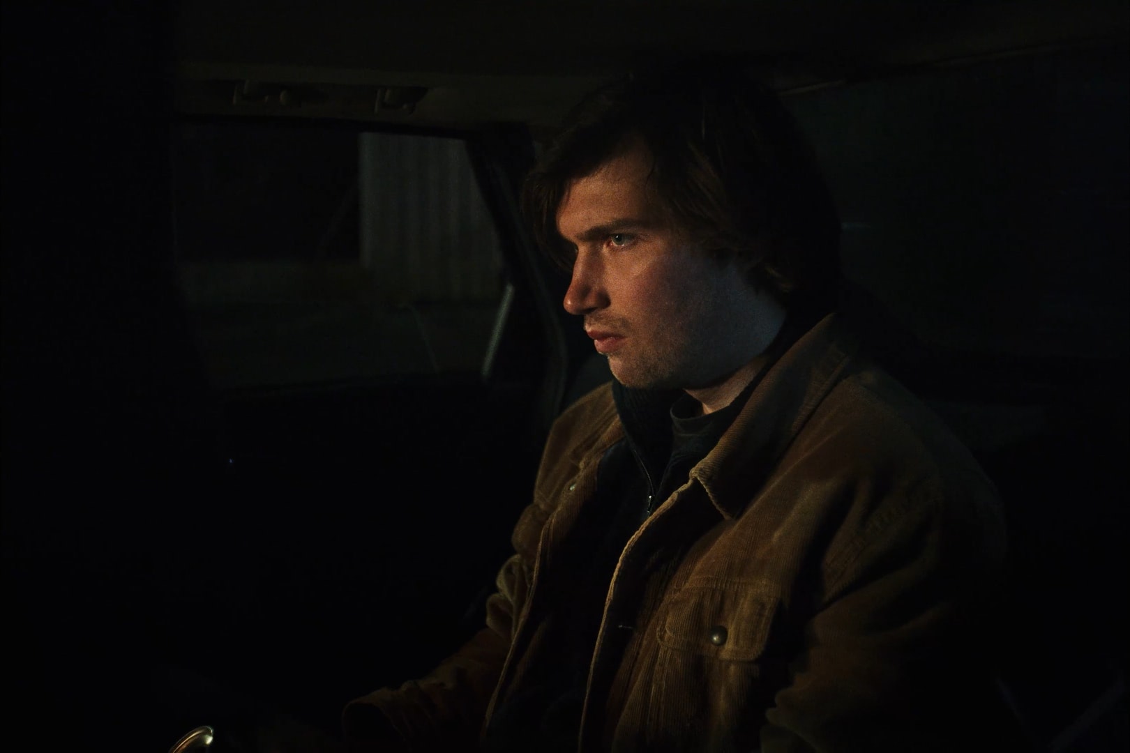 A man sitting inside a car at night.