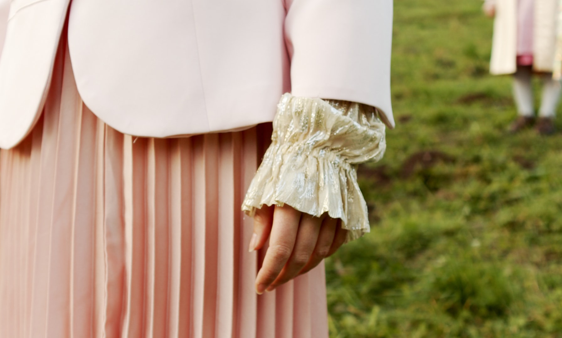 Detail of a pleated cuff covering a hand. 