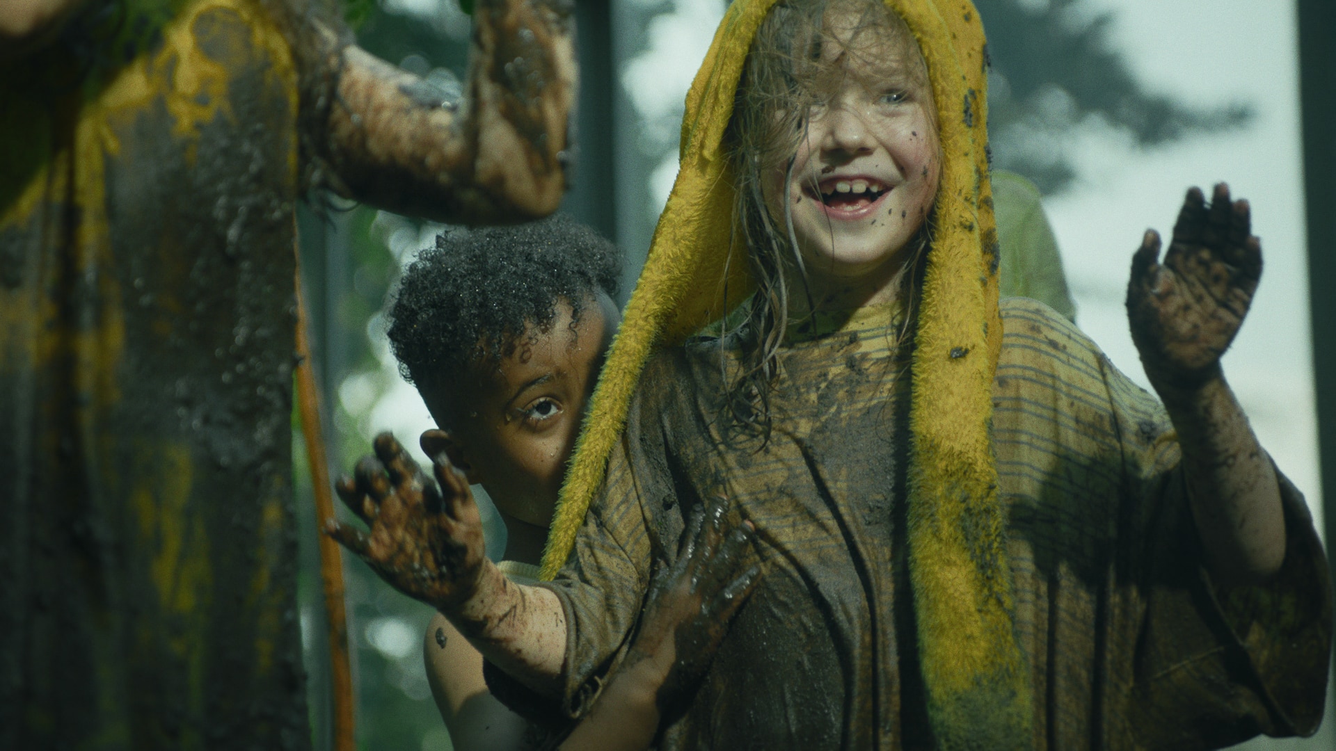 Several kids, drenched in mud, playing and dancing.