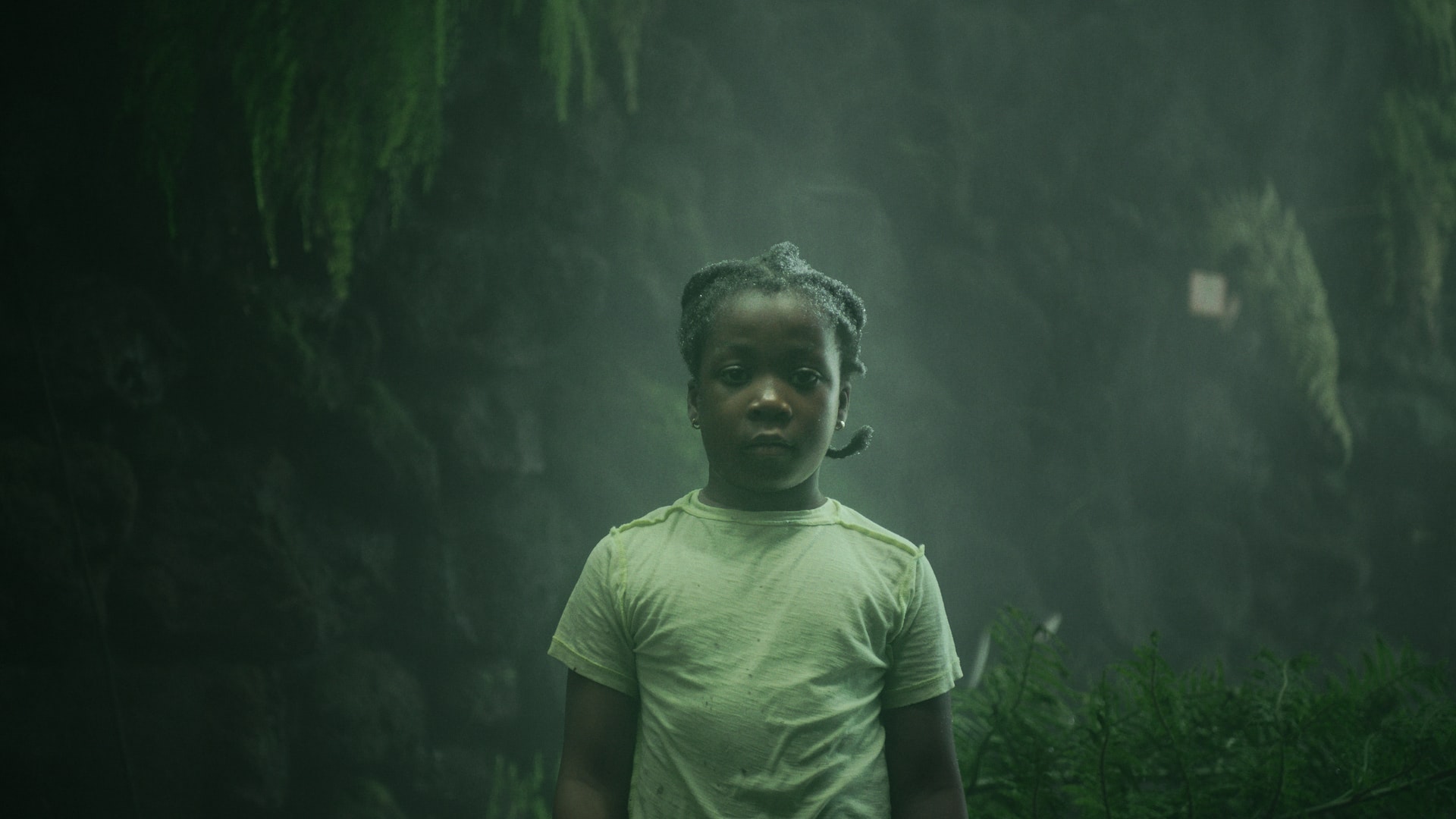 A young girl standing in the mist, with droplets of water in her hair.